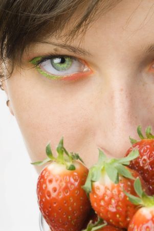 portrait of a young and cute brunette with big strawberry painted on her face and colored eyesの写真素材
