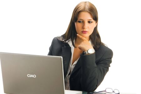 a white collar worker in formal black tailleur sitting at her desk  working with a computer and having an expressive faceの写真素材