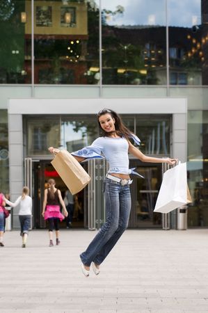 beautiful brunette jumping with her shopping bags after a hard day in commercial centerの写真素材