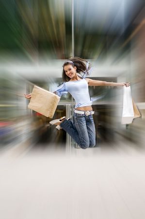 beautiful brunette jumping with her shopping bags after a hard day in centerの写真素材