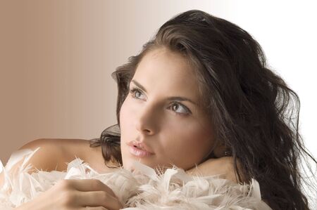 cute portrait of a beautiful brunette with the face laying down on some feathersの写真素材