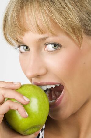 close up of a nice blond woman eating a green appleの写真素材