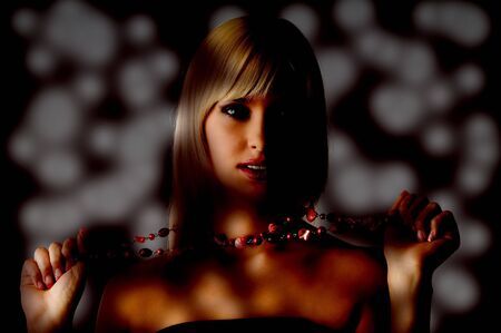 cute blond girl with glamour make up pulling a red necklaceの写真素材