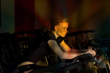 nice girl doing spinning in a gym club with colored light effect