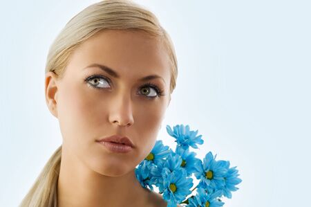 pretty blond girl in a beauty portrait with blue daisy on her shoulder
の写真素材