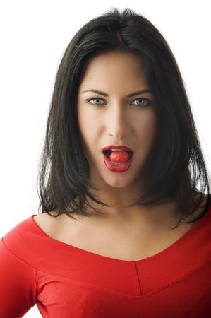 portrait of beautiful brunette with red lips red top and a red candy between teethの写真素材