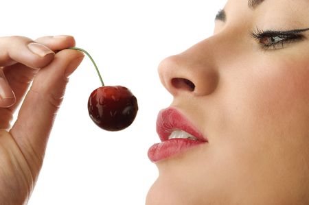 close up of cute woman with red lips keeping wet cherry near faceの写真素材