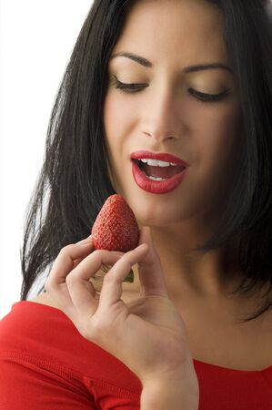 pretty woman with red lips looking a strawberry and making faceの写真素材