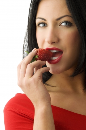 beautiful and sensual brunette girl eating a strawberry with red lipsの写真素材