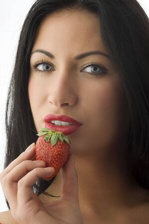 pretty brunette with a strawberry near her mouth with red lipsの写真素材