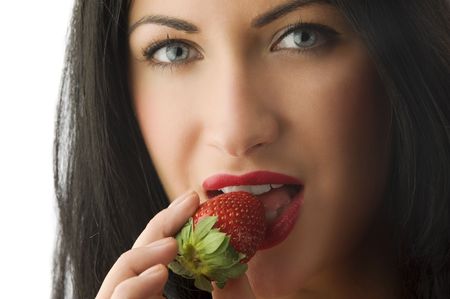close up on face of beautiful brunette girl with red lips eating a strawberry の写真素材