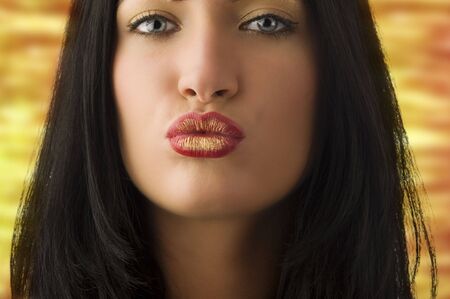 beautiful young woman with dark hair and creative lips giving a kissの写真素材