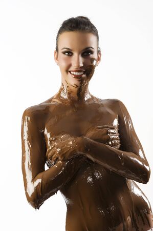 amazing shot of a young beautiful brunette with her naked body covered of sweet cream chocolateの写真素材