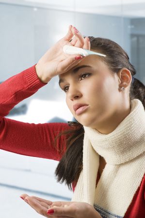portrait of young brunette with red sweater and white scarf looking very sickの写真素材