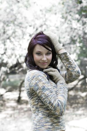 pretty young brunette in a forest in winter with a nice and sweet colored pulloverの写真素材