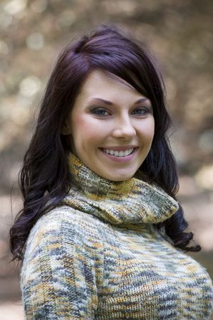 pretty young brunette in a forest with a nice colored pullover smiling
の写真素材