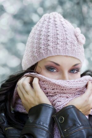 cute girl with stunning eyes covering her face from a cold winter with pink scarf の写真素材