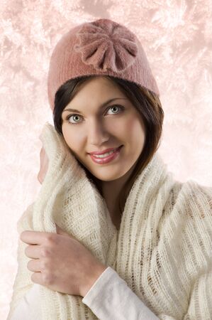 pretty sweet girl warming herself  with white scarf and a pink winter cap in a studio shotの写真素材