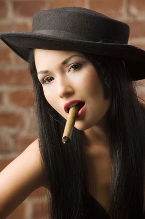 very cute asian girl with a black hat smoking a cigarの写真素材