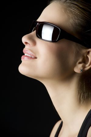 profile close up of blond woman smiling with eyeglasses on black backgroundの写真素材
