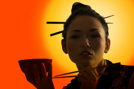 beautiful asian girl in japanes dress on sunset with cup and chopstickの写真素材