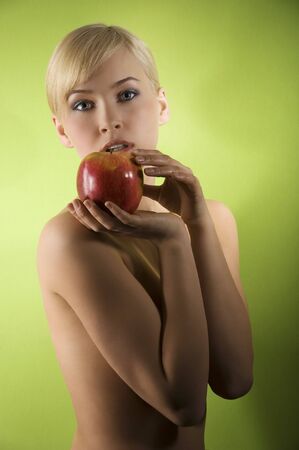 fashion and glamour shot of a nude young woman with apple on green background の写真素材