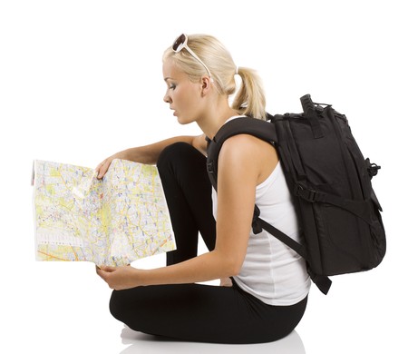 young pretty student girl in vacation sitting down and looking for place on a mapの写真素材
