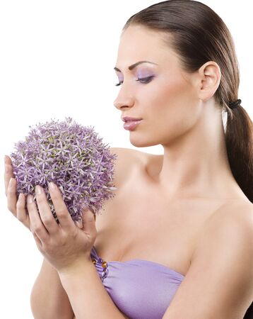one side beauty shot of youn and pretty brunette looking at some purple flowersの写真素材