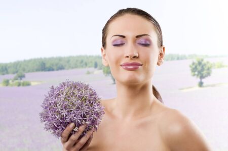 young and beautiful brunette woman in a beauty portrait with some purple flower near faceの写真素材