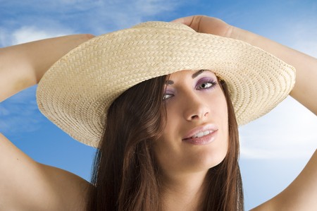 closeup portrait of pretty brunette woman wearing a nice summer hat with long hairの写真素材