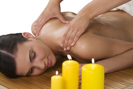 attractive beautiful caucasian woman lying down on a massage bed at a spa with candleの写真素材