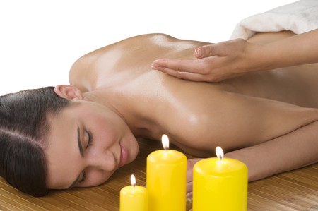 attractive beautiful caucasian woman lying down on a massage bed at a spa with candleの写真素材