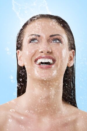 fresh portrait of a young woman with her face wet looking up and laughingの写真素材