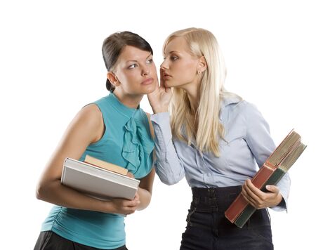 two nice girl blond and brunette with book like student one wishpering to the otherの写真素材