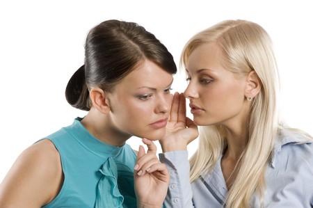 close up of a blond and a brunette girl wishpering as close friendsの写真素材