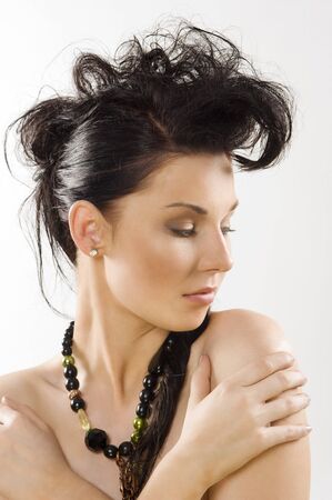 close up portrait of cute brunette with necklace and creative hair style looking on one sideの写真素材