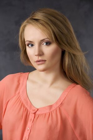 fashion beauty portrait of young woman with hair style over dark background wearing an orange shirtの写真素材