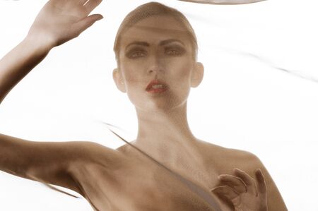 creative portrait of very beautiful brunette girl behind transparet brown material の写真素材