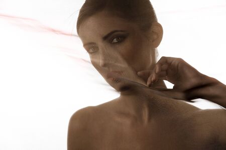 close up portrait of a girl behind a transparent veil of brown materialの写真素材