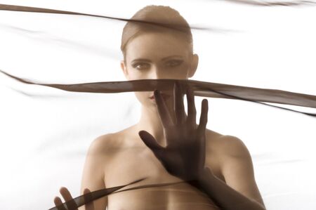 art fashion portrait of naked woman behind transparent material showing her breastの写真素材