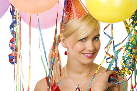 portrait of blond woman in a party between colored ribbons and balloons looking and smilingの写真素材