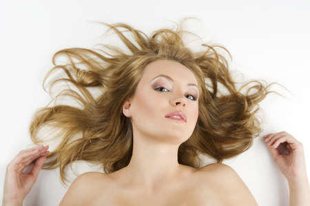 beauty portrait of young blond woman in black underwear with hair style laying down on white の写真素材