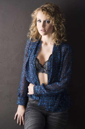 sexy blond curly haired woman in blue shirt and bra on black background の写真素材