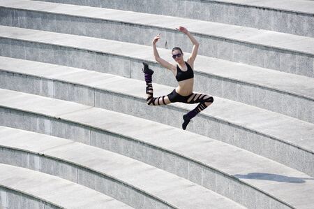 young cute dancer woman jumping outside in urban arena theaterの写真素材