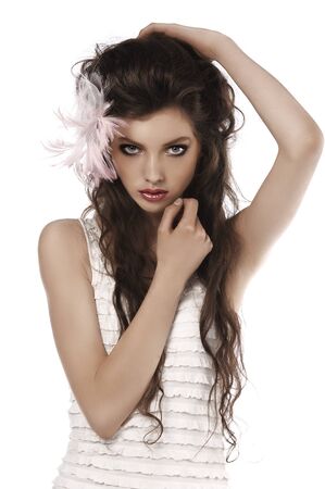 young fashion brunette posing on white wearing a pink feather in her hairの写真素材
