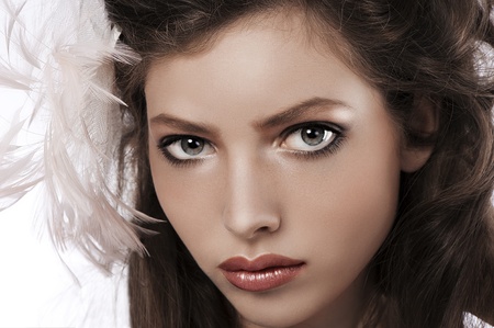 beauty portrait of a pretty girl with big grey eyes wearing a soft pink feather accessory in her hairの写真素材