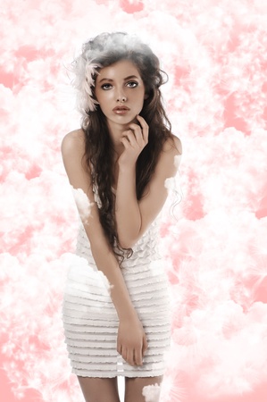 young fashion brunette with long curly hair posing on whiteの写真素材