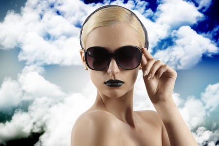fashion portrait of young blond woman with hair style black lips and wearing sunglasses looking at the camera against white backgroundの写真素材