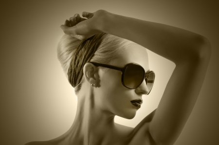 fashion portrait of young blond woman with hair style black lips and wearing sunglasses posing against white background