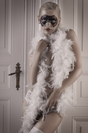 pretty blonde girl wearing a feather boa and panties posing in a doorwayの写真素材